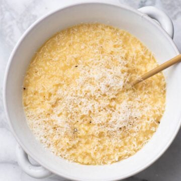 Pastina with shaved parmesan cheese and a spoon in a bowl.