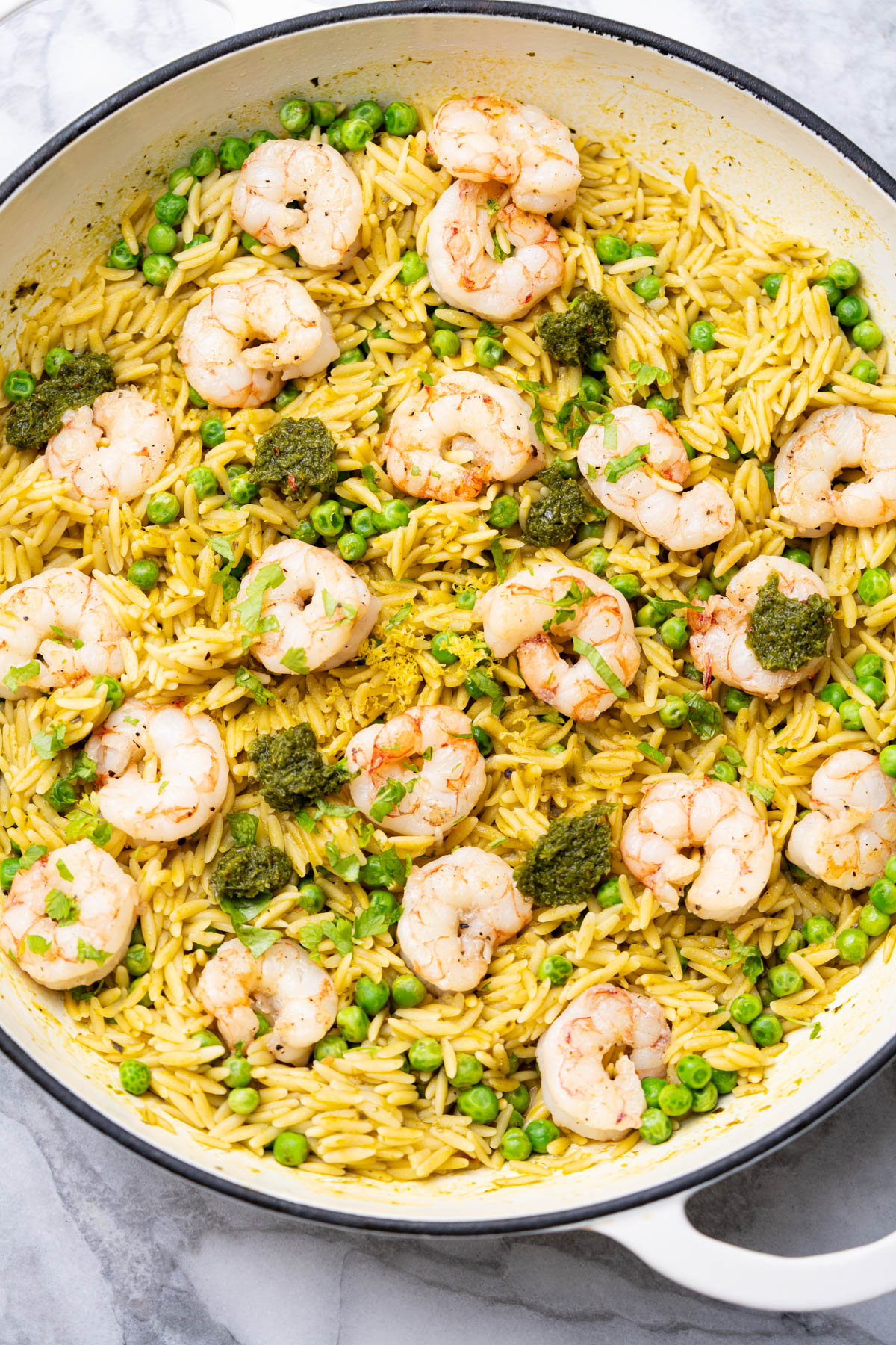 Shrimp with orzo and peas on a skillet.