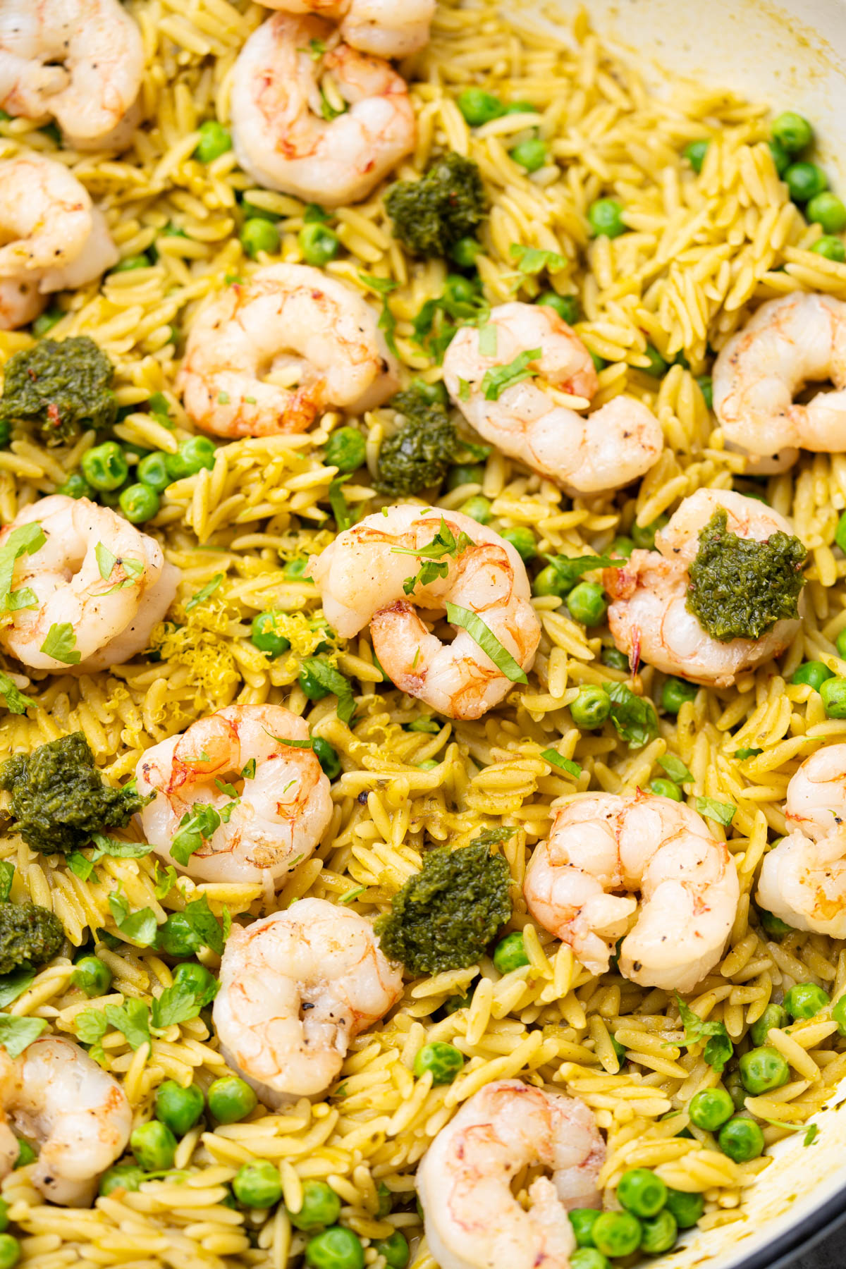 Orzo with chimichurri sauce, peas and shrimp in a skillet.