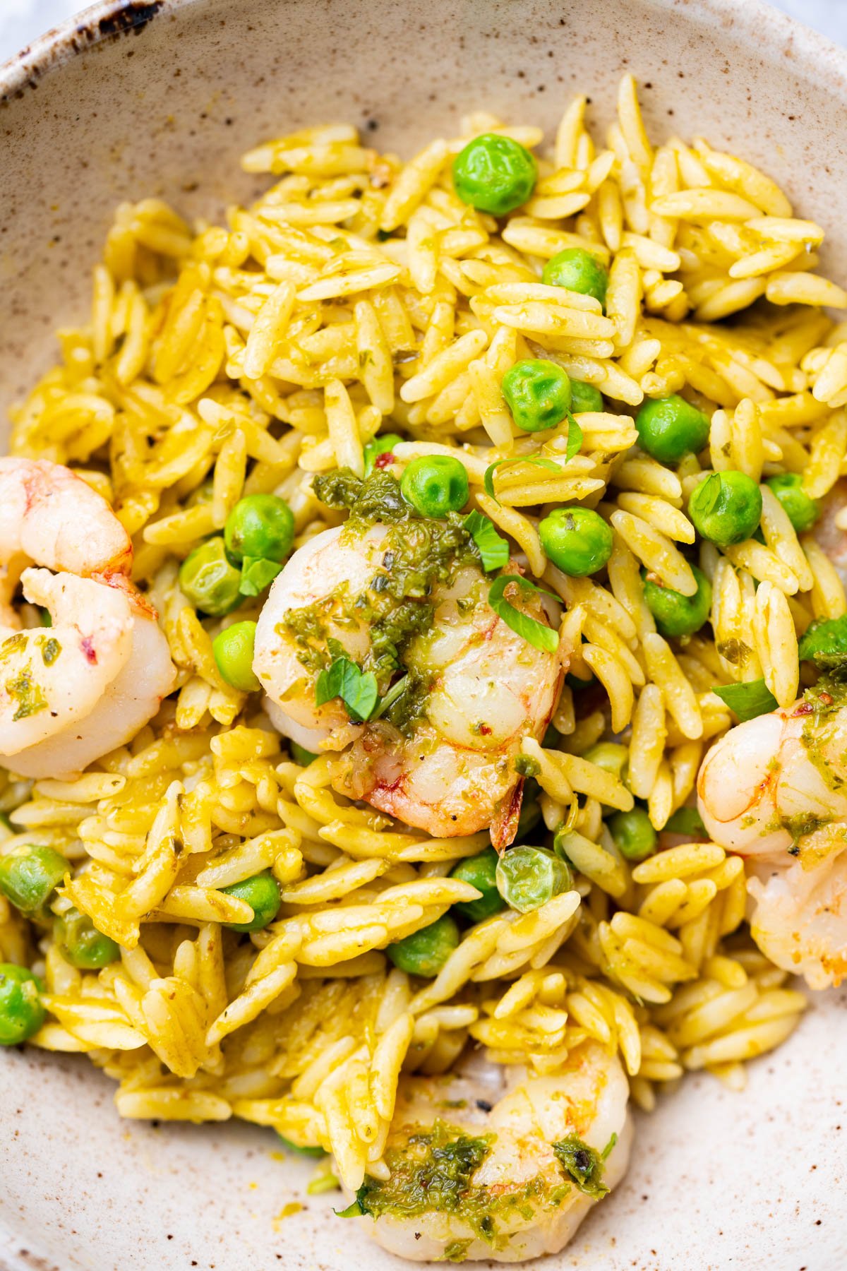 Orzo with chimichurri sauce, peas and shrimp on a bowl.