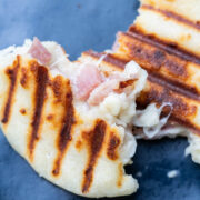 Colombian arepas stuffed with cheese and ham on a blue plate.