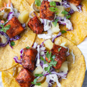 Salmon bites tacos over yellow corn tortillas with coleslaw.