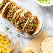 Arepas con carne desmechada in a basket. Served with guacamole, cheese and plantain chips.