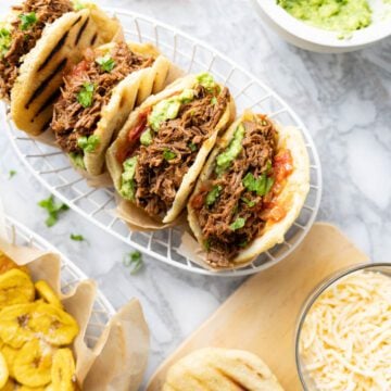 Arepas con carne desmechada in a basket. Served with guacamole, cheese and plantain chips.