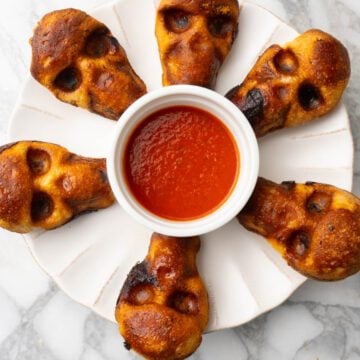 Pizza skulls with pizza sauce on a platter for halloween party.