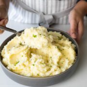 Boursin mashed potatoes with butter and chives in a grey serving plate.