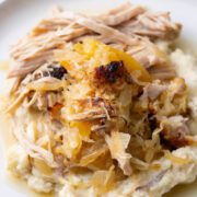 Pork loin with sauerkraut and apples on a plate with mashed potatoes.