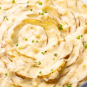 Scalloped potatoes in a baking dish garnished with herbs.