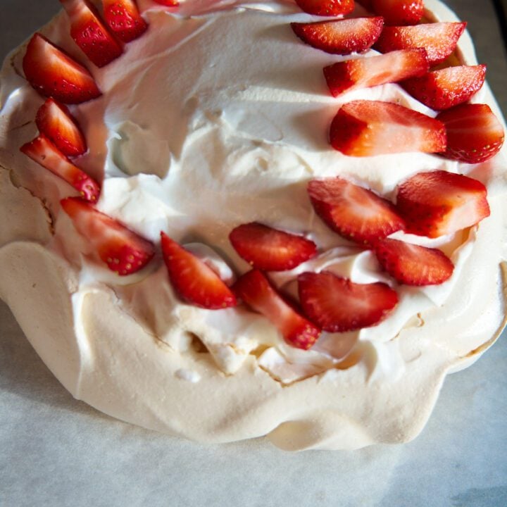 Strawberry pavlova on a baking tray with parchment paper.
