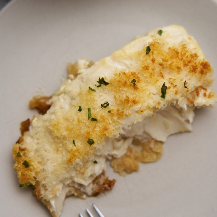 Halibut with crumb topping on a plate with a fork.