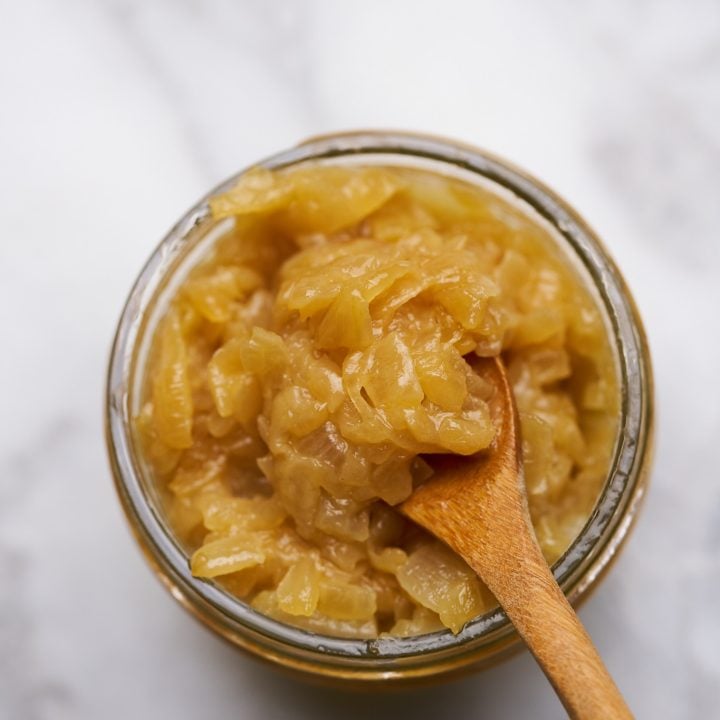 Simple caramelized onions on a jar with a wooden spoon.