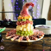 Charcuterie witch hat with grapes, cheese, salami and prosciutto placed on a cake stand.