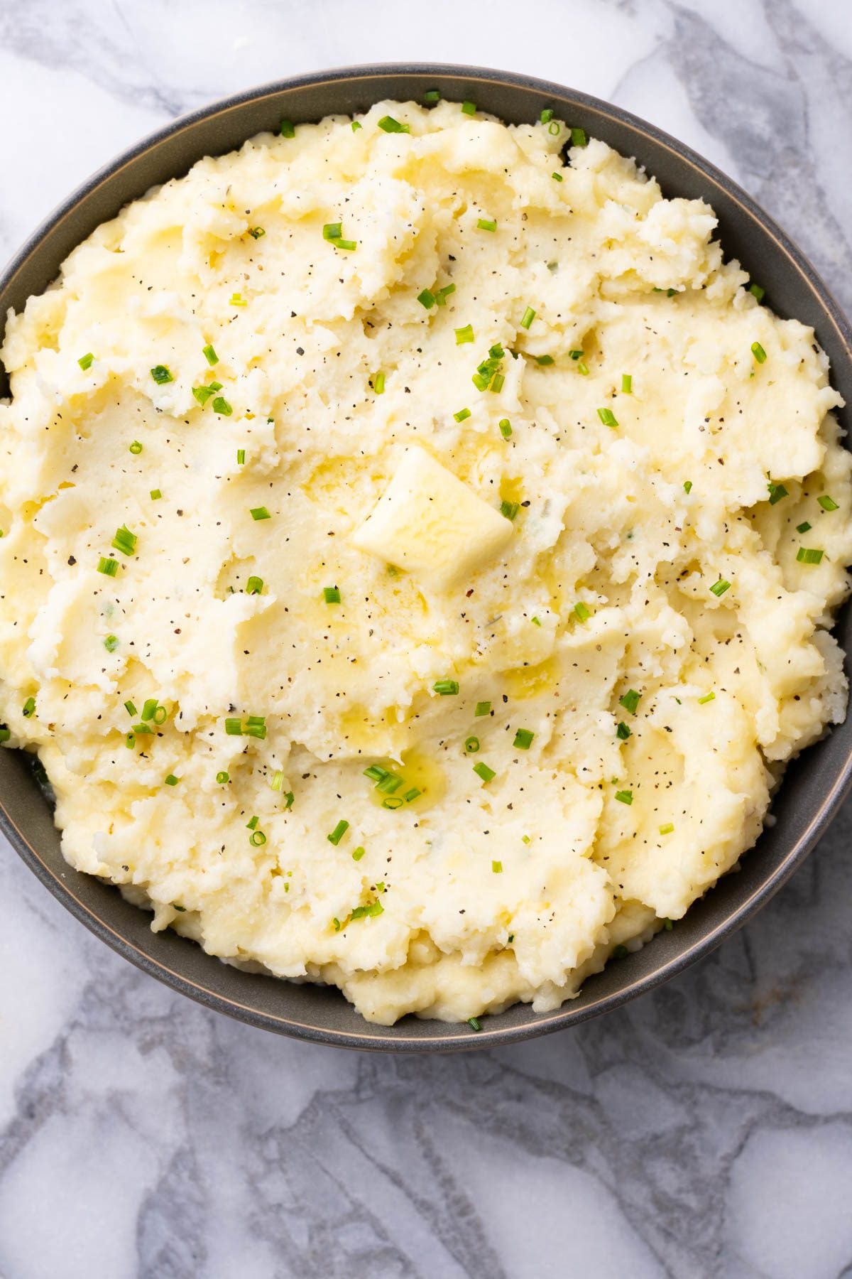 Boursin mashed potatoes with butter and chives in a grey serving plate.