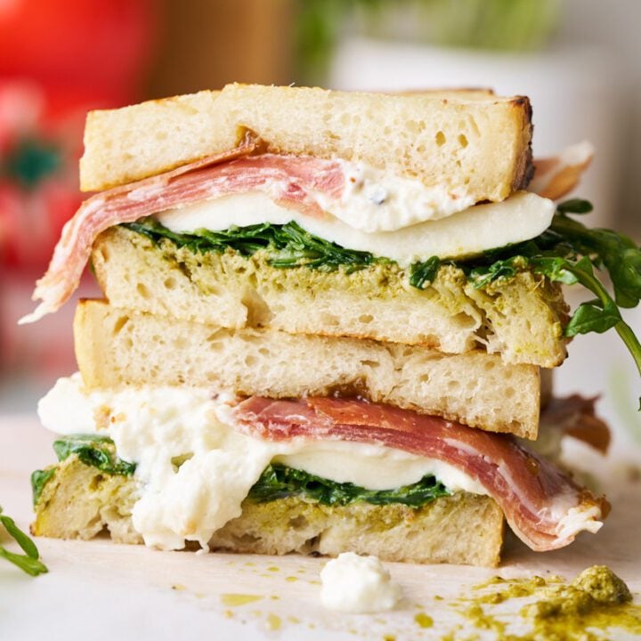 Prosciutto and burrata sandwich with pesto and arugula on sourdough bread.