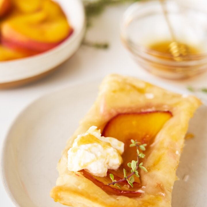 Peach and Burrata Upside Down Puff Pastries with honey and thyme on a plate.