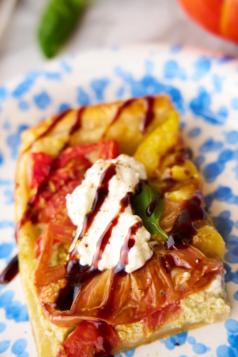 Puff pastry tart with tomatoes on a plate.