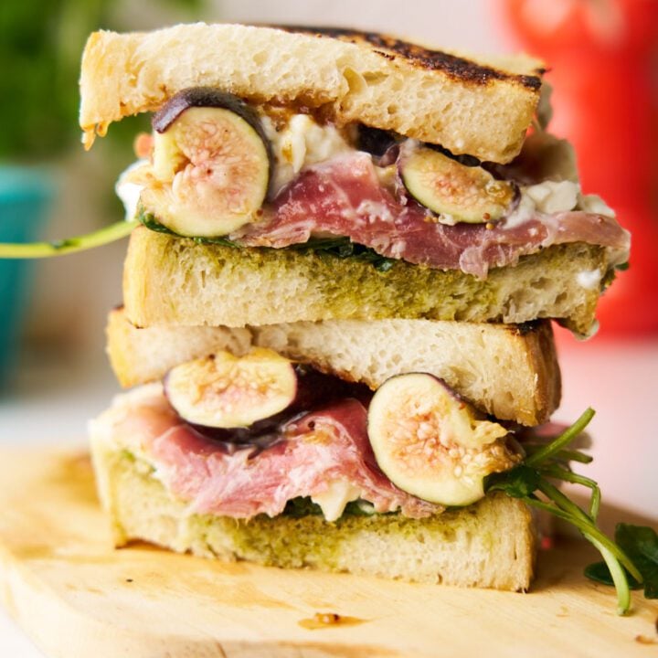 Fig, burrata and prosciutto sandwich on a wooden board.