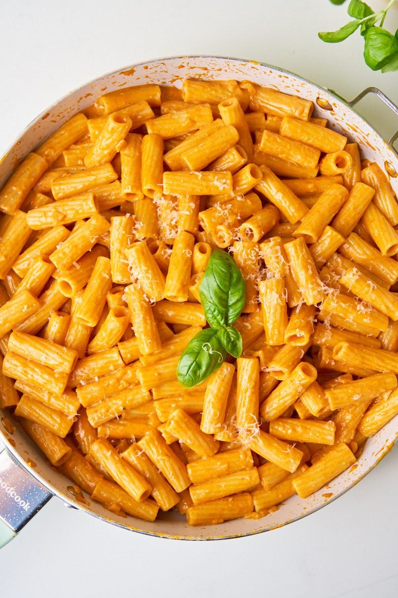 Creamy rigatoni alla vodka with basil and parmesan cheese on a skillet.